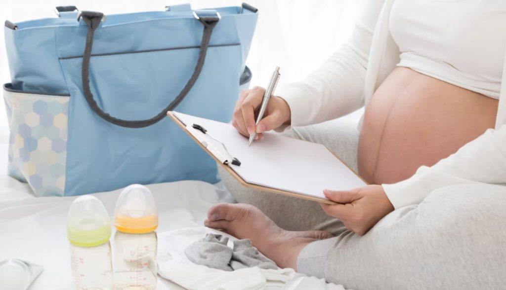 pregnant woman writing list with blue bag