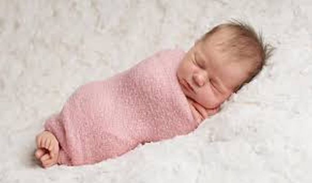 baby sleeping in pink swaddle blanket