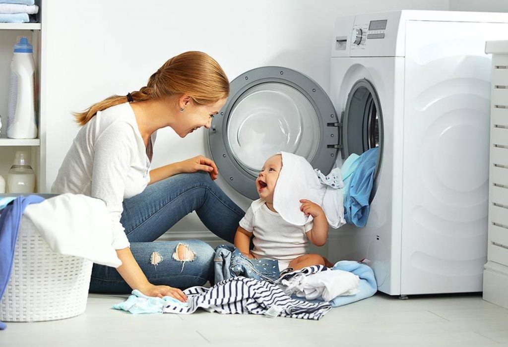 happy mother and baby sitting in front of washing machine