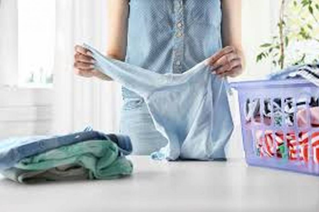 mother folding washing of baby clothes