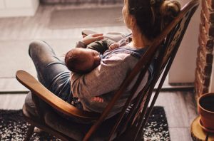 mother rocking baby to sleep in rocking chair