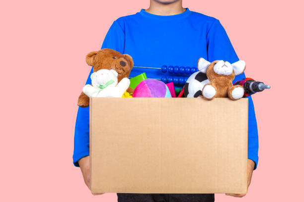 donation concept. kid holding donate box with clothes, books and toys.