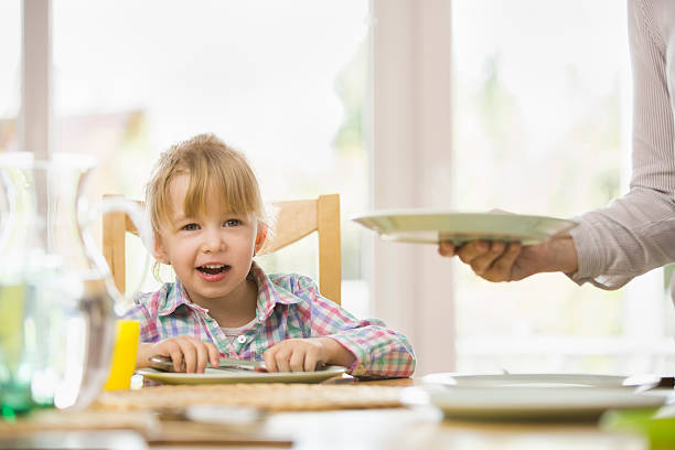 young mother is setting the table for her family for lunch.