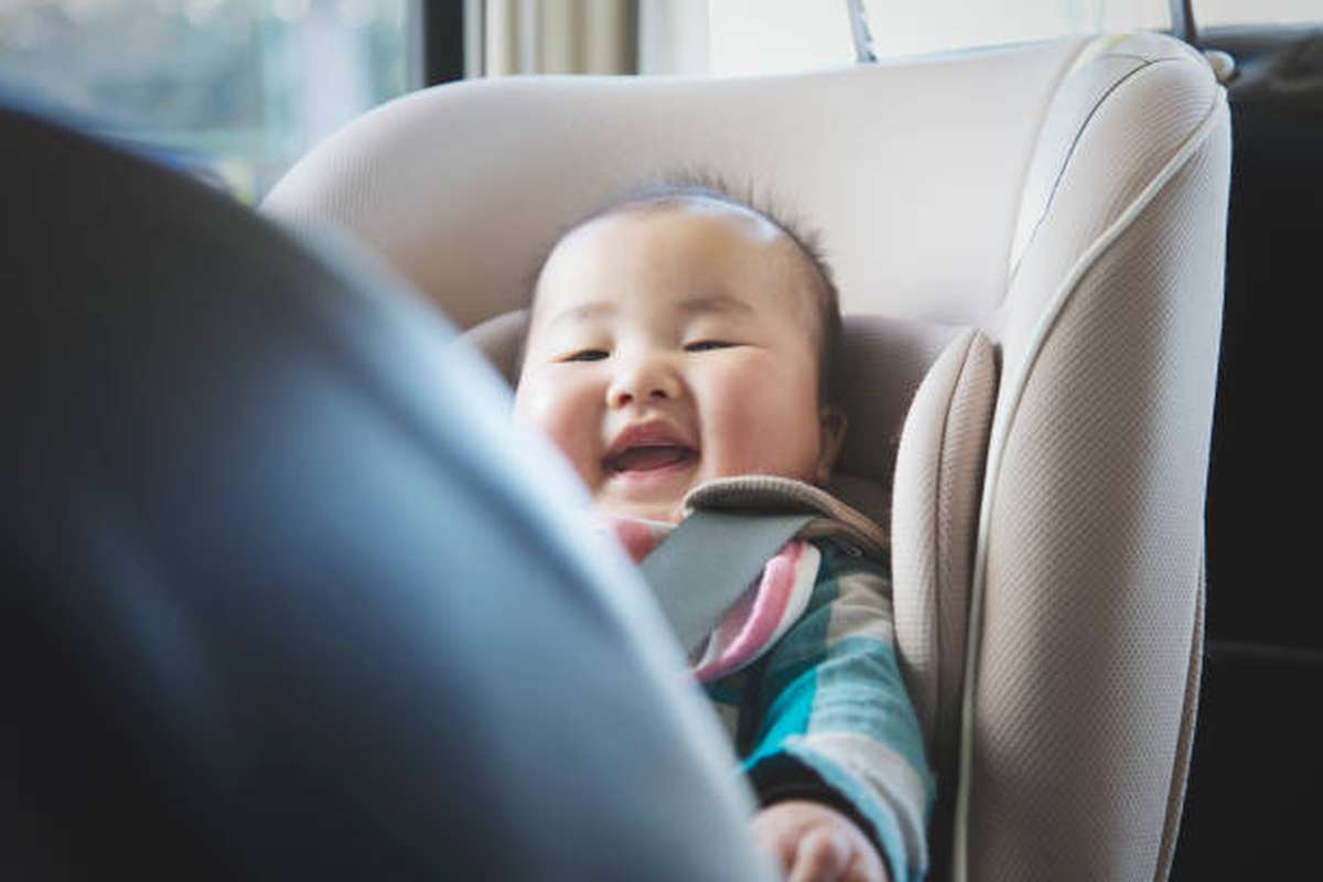asian smiling baby girl sitting on safety seat in a car.