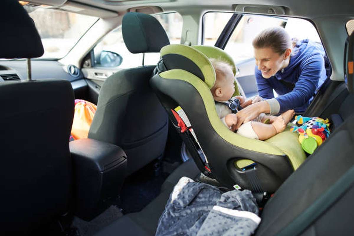 portrait of a mother fastening her baby boy safely in a car seat